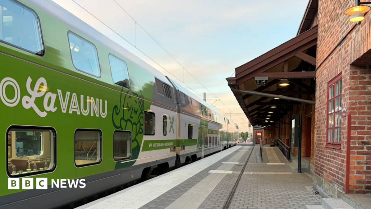 A blue train with Lumo branding travelling under overhead wires.